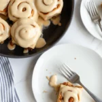 Freshly baked cinnamon rolls with cream cheese frosting served on a plate