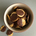 A bowl filled with ridged potato chips partially coated in rich chocolate, highlighting their sweet-and-salty appeal.
