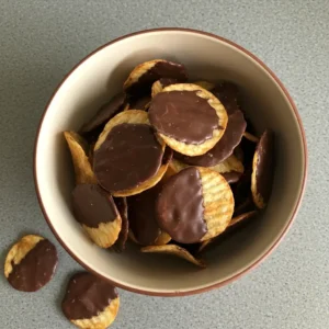 A bowl filled with ridged potato chips partially coated in rich chocolate, highlighting their sweet-and-salty appeal.