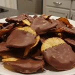 A plate of crispy, ridged potato chips partially dipped in smooth chocolate, showcasing a sweet-and-salty contrast.