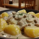 Close-up of potato stroganoff featuring tender boiled potatoes smothered in a creamy mushroom sauce.