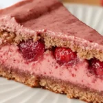 Close-up of a slice of vegan raspberry cream tart with visible fresh raspberries and nut-based crust.