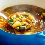 Bowl of homemade garden vegetable soup with fresh vegetables