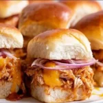 BBQ chicken sliders served on a platter with fresh toppings