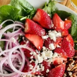 Fresh Strawberry Spinach Salad with nuts and dressing on a plate